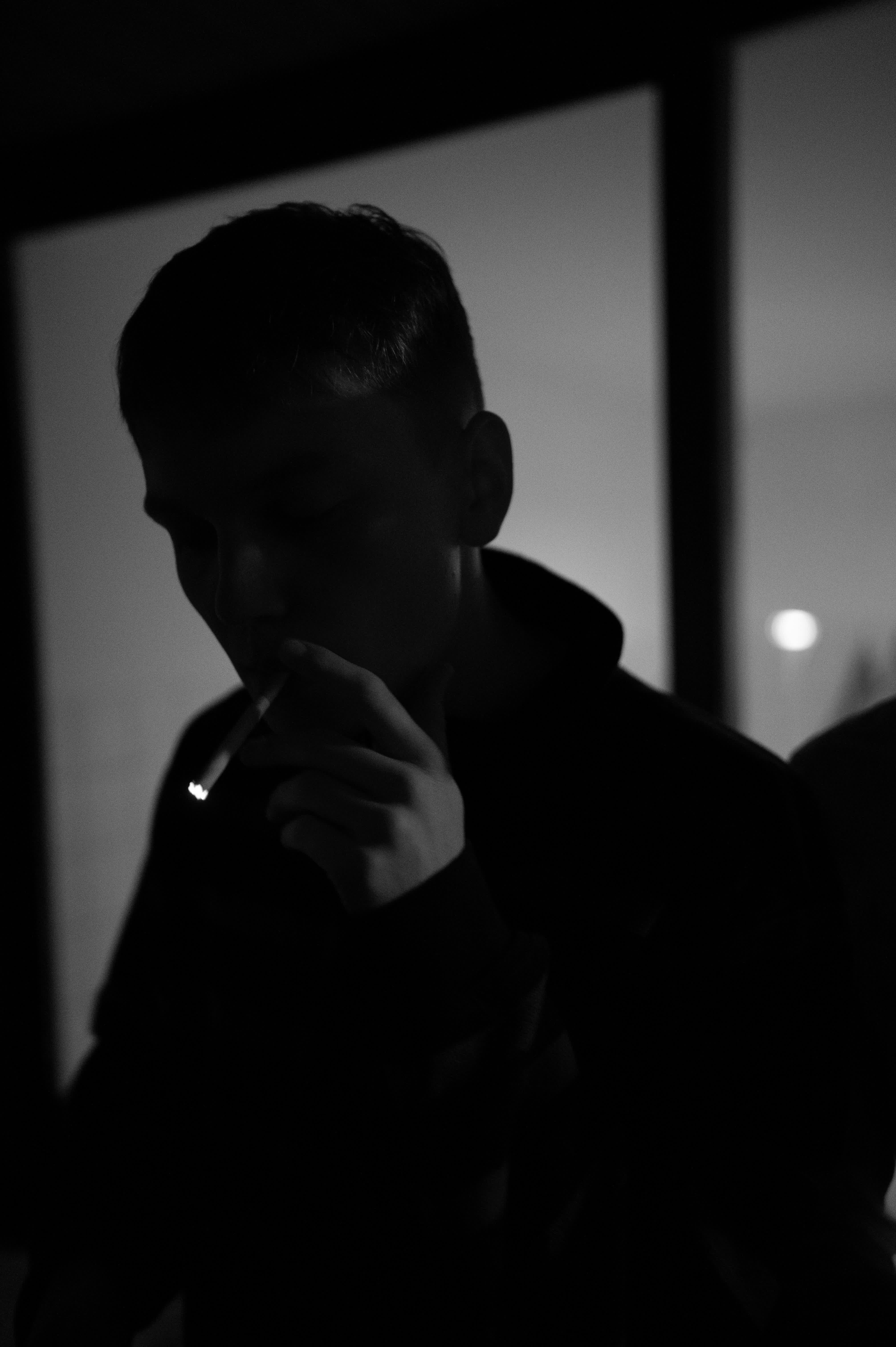 Rauchender Jugendlicher auf einem Balkon im Dunkeln bei Nacht