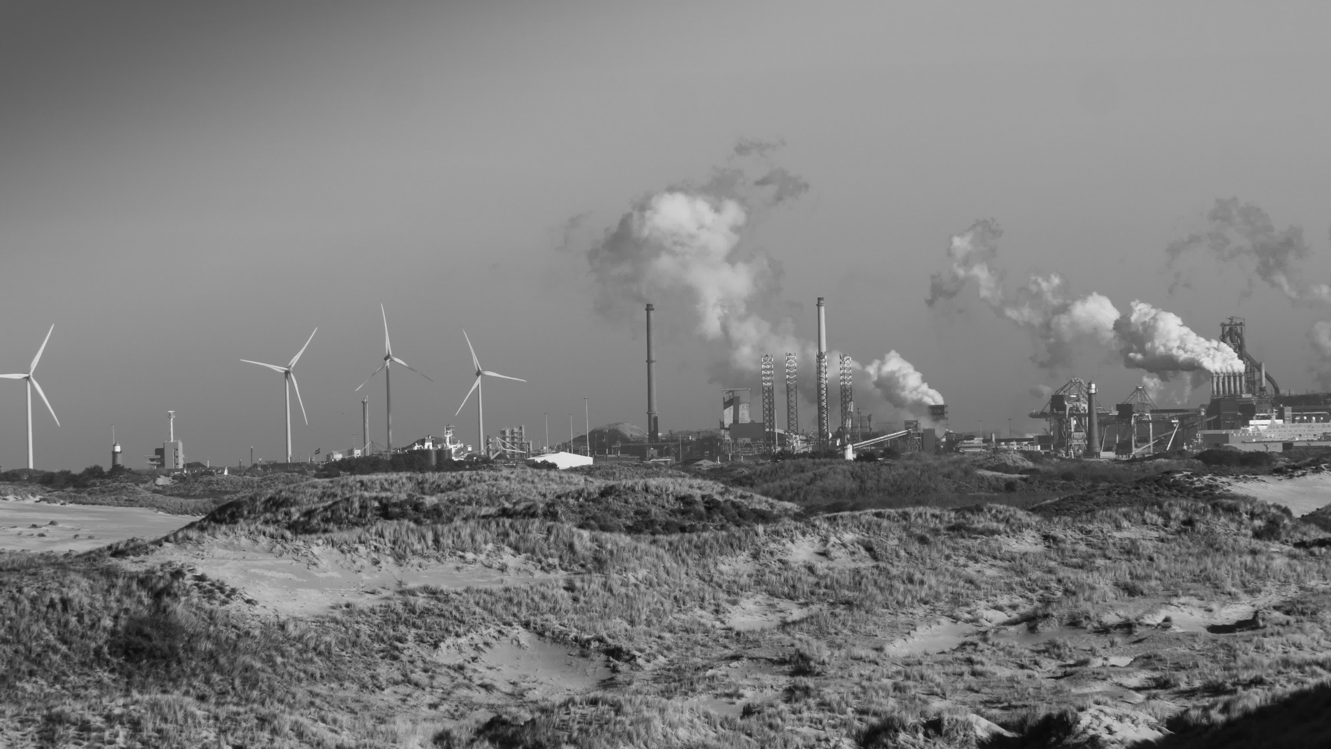 Dünenlandschaft mit Industriepark im Hintergrund in schwarz-weiß